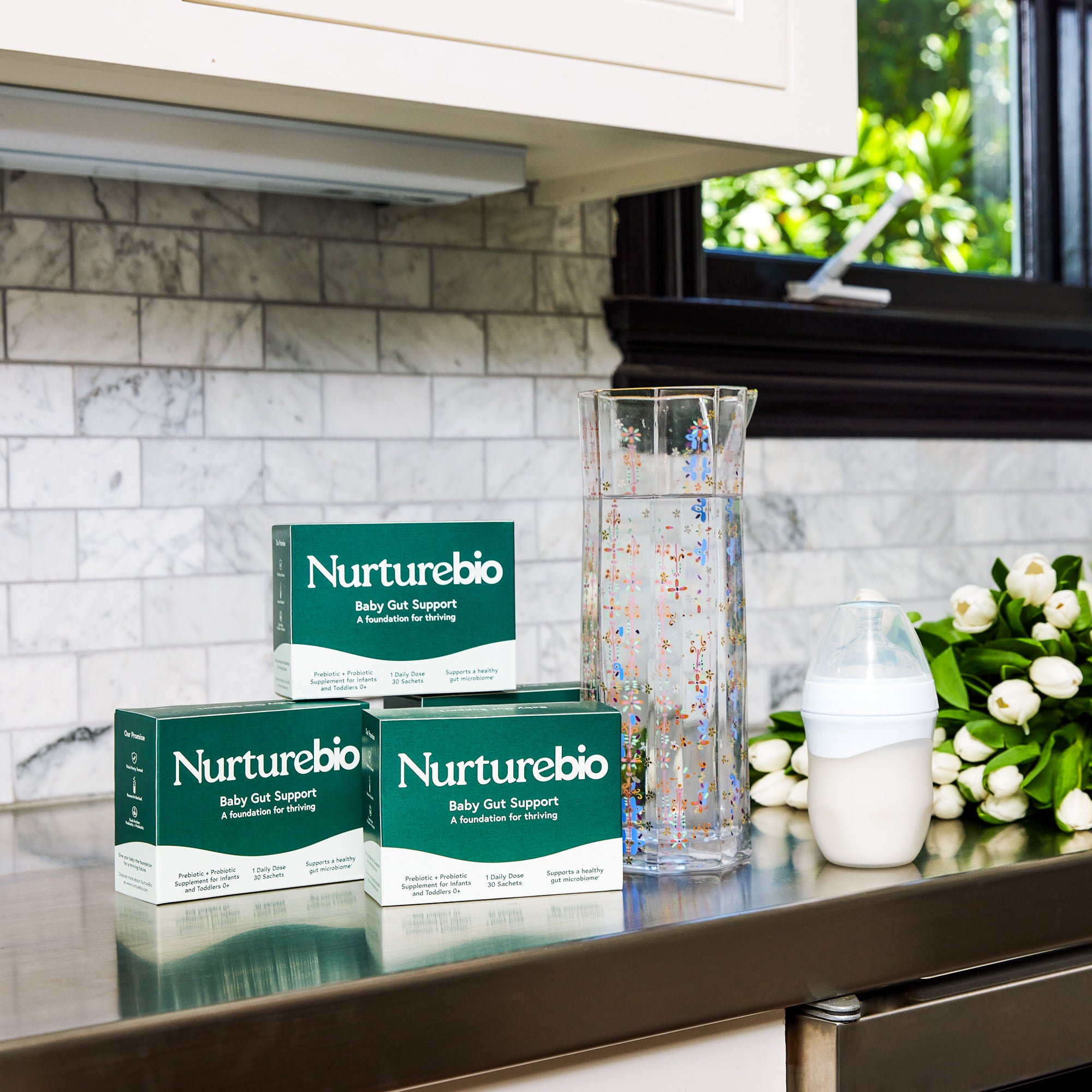 Nurturebio synbiotic supplements on a kitchen counter with a vase and flowers in the background.