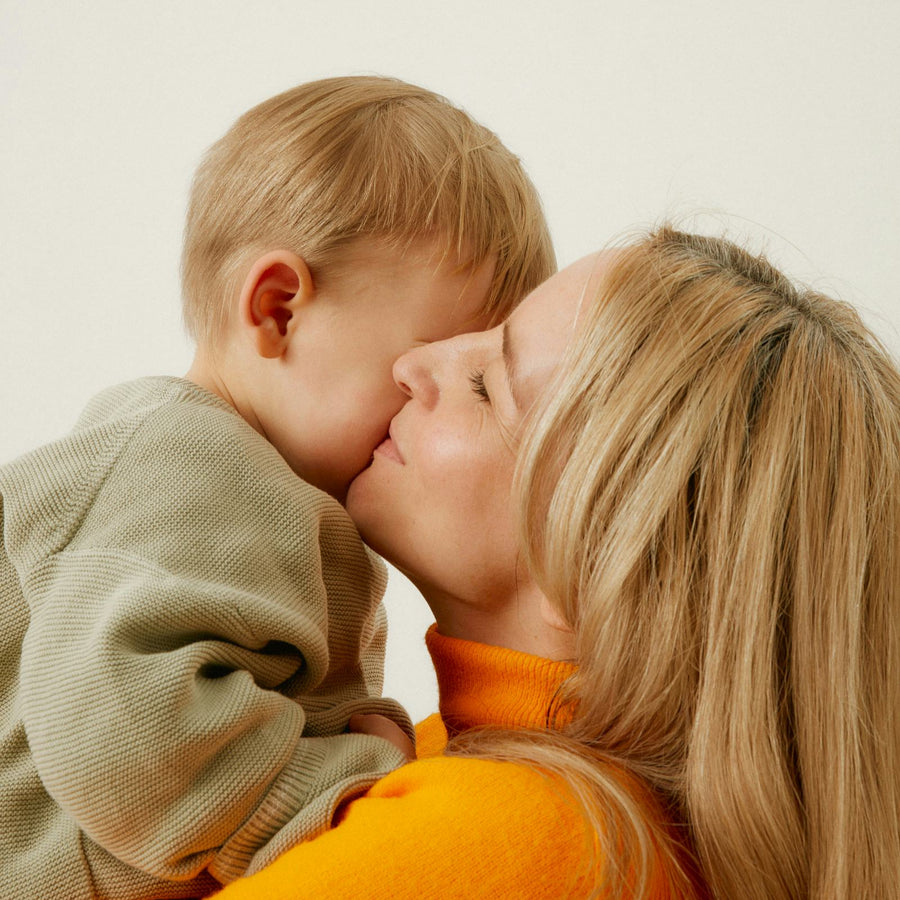 A mother kissing her young child on the cheek