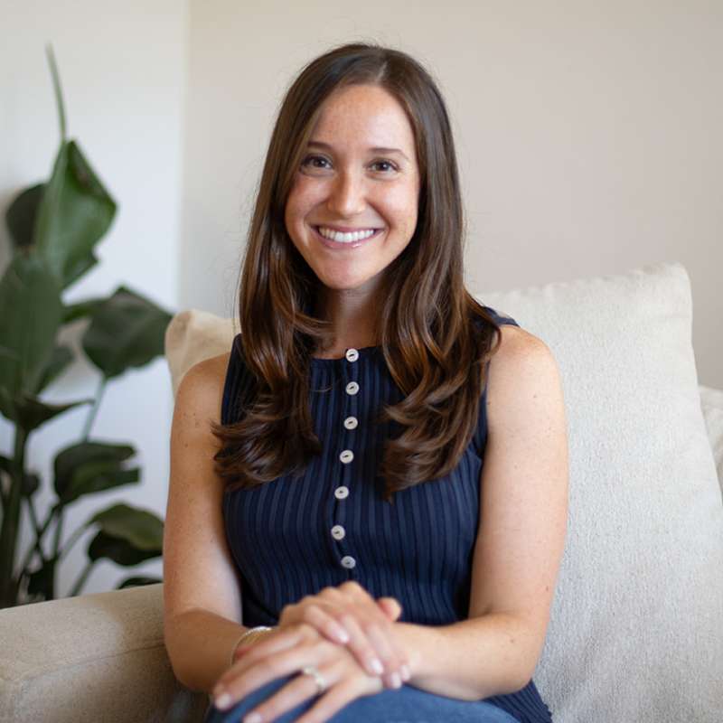 Woman sitting on a couch with a plant in the background
