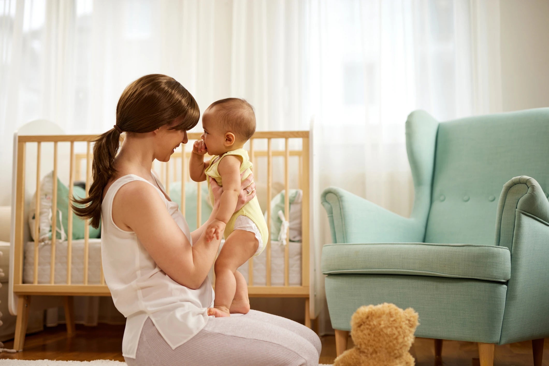 Mother holding her baby in a warm, sunlit nursery