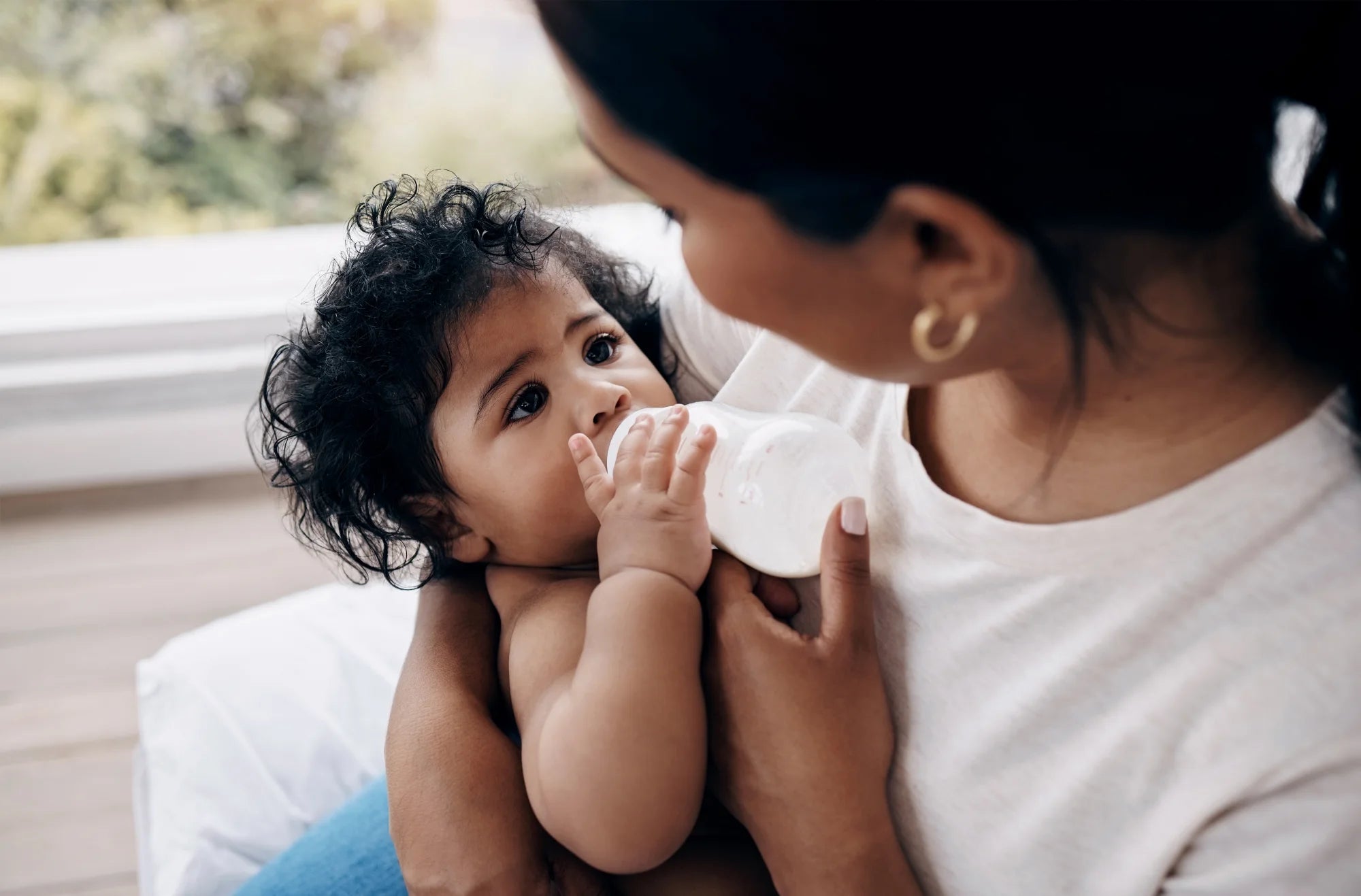 Mother feeding her baby with a bottle at home